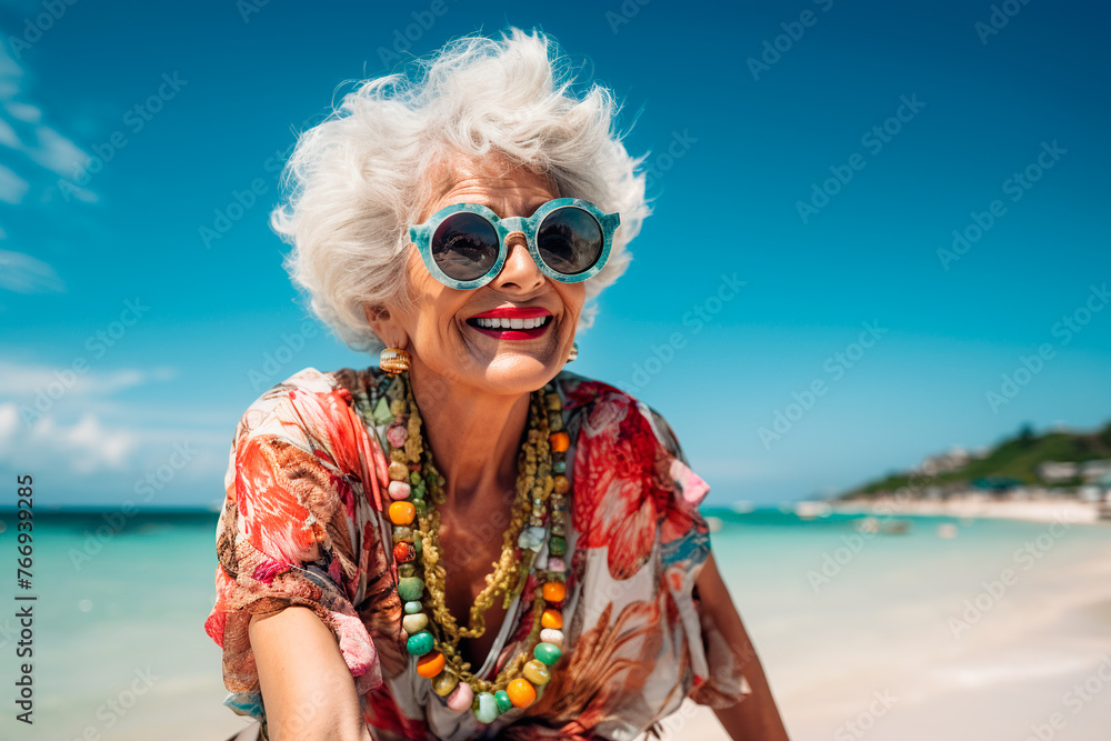 Beautiful cheerful granny in sunglasses close-up on the beach, portrait