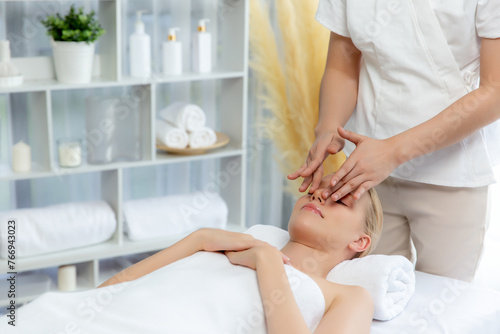 Caucasian woman enjoying relaxing anti-stress head massage and pampering facial beauty skin recreation leisure in dayspa modern light ambient at luxury resort or hotel spa salon. Quiescent