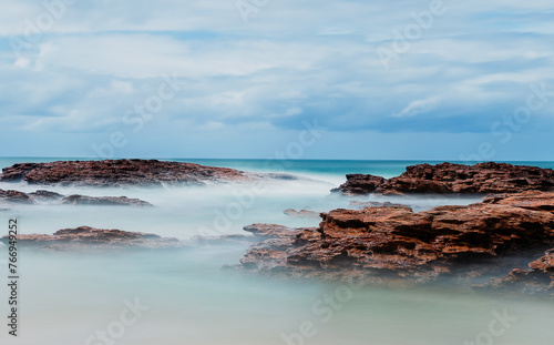 Ocean waves crashing on rocks on beach. Coffs Harbour, Australia.