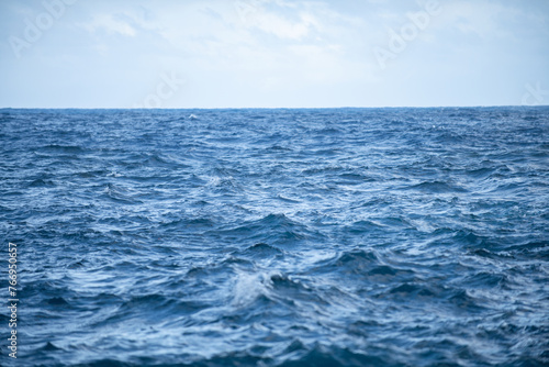 Calm sea water surface texture with splashes and waves. Abstract nature background. Background of aqua ocean water surface.