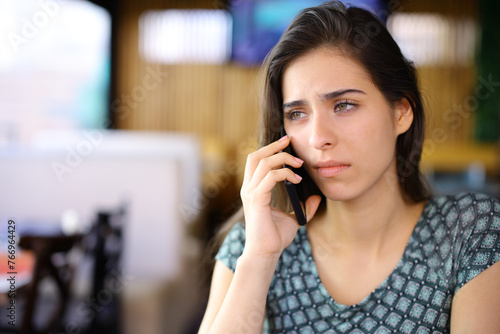 Sad woman talking on phone in a bar