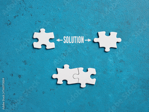 The word solution with puzzle pieces on blue background.