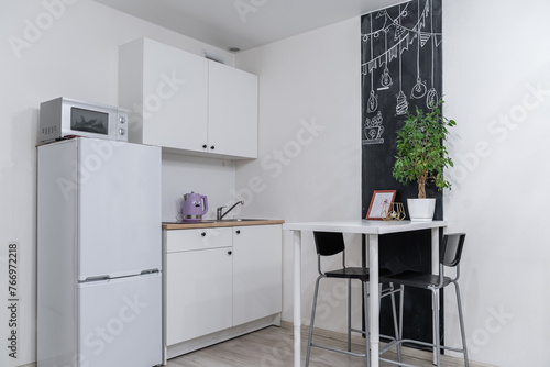 a small modern bright kitchen with grey furniture and household appliances