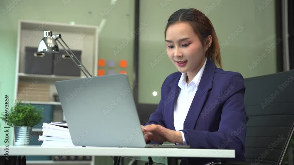 businesswoman talking mobile phone and working on laptop and papers on table in her office. businesswoman talking mobile phone and working on laptop and papers on table in her office.