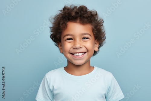 Cheerful little boy looking at camera with toothy smile, over blue background