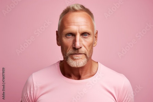 Portrait of a senior man in pink t-shirt on a pink background.