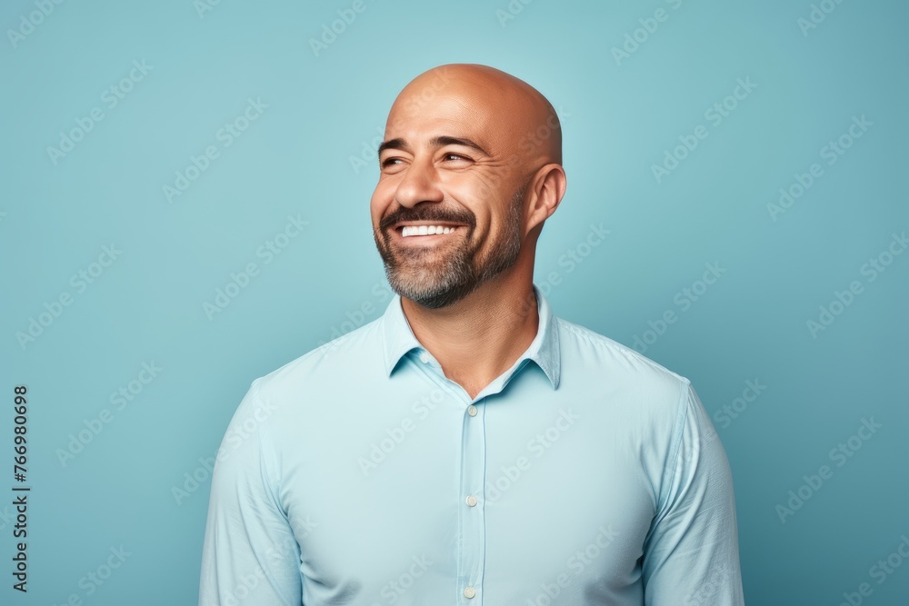 Cheerful mature man in casual shirt looking at camera and smiling while standing against blue background