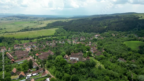 Viscri - Beautiful saxon village in the heart of Romania. Famous travel destination. Green landscape, agriculture fields. Drone circling around the village photo