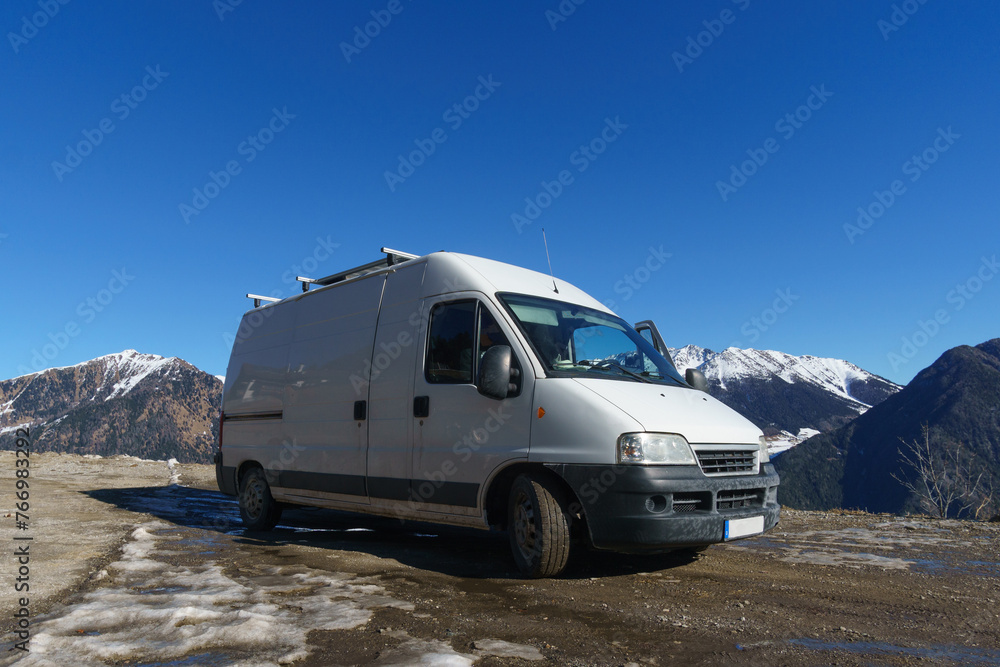 Camper van on road trip in alpine mountain landscape during winter time near the border of Austria on the pass road of Pennes, South Tirol, Italy