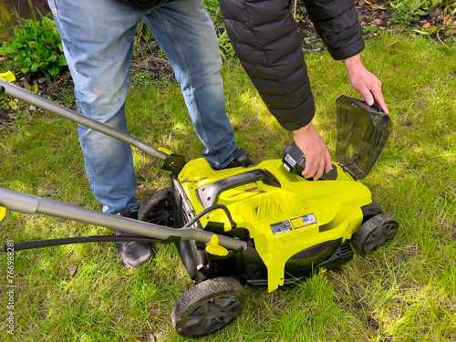 Inserting a battery into electric cordless lawn mower