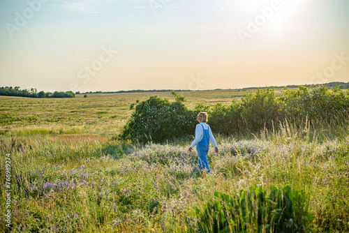 entspannte junge Frau mit Sonnenbrille läuft auf einer Blumenwiese
