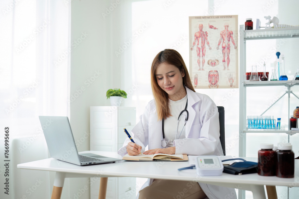 Young Asian woman or female medical staff sitting smiling, arms looking happily at camera, working on table in clinic office in telehealth, telemedicine, consulting online service. Young Asian woman or female medical staff sitting smiling, arms looking happily at camera, working on table in clinic office in telehealth, telemedicine, consulting online service.