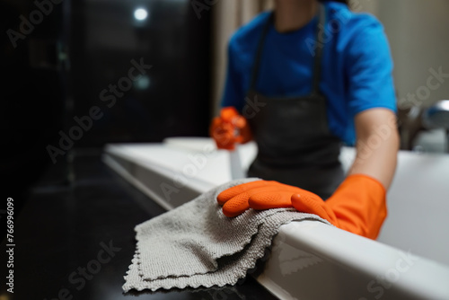 Cleaning online service. yong woman housekeeper cleaning bathtub in bathroom with a cloth. House cleaning service concept