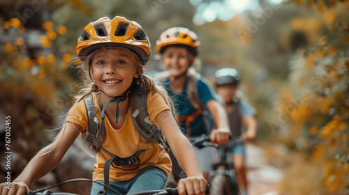 Cute little girl in helmet riding a bicycle with her friends in the park