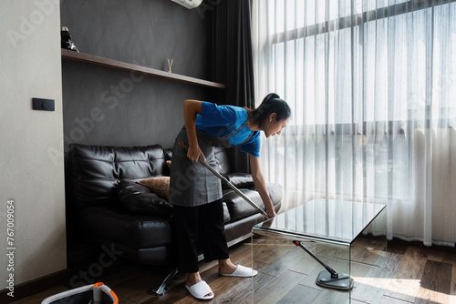 cleaning service housekeeper women swipe floor in living room. House cleaning service concept photo