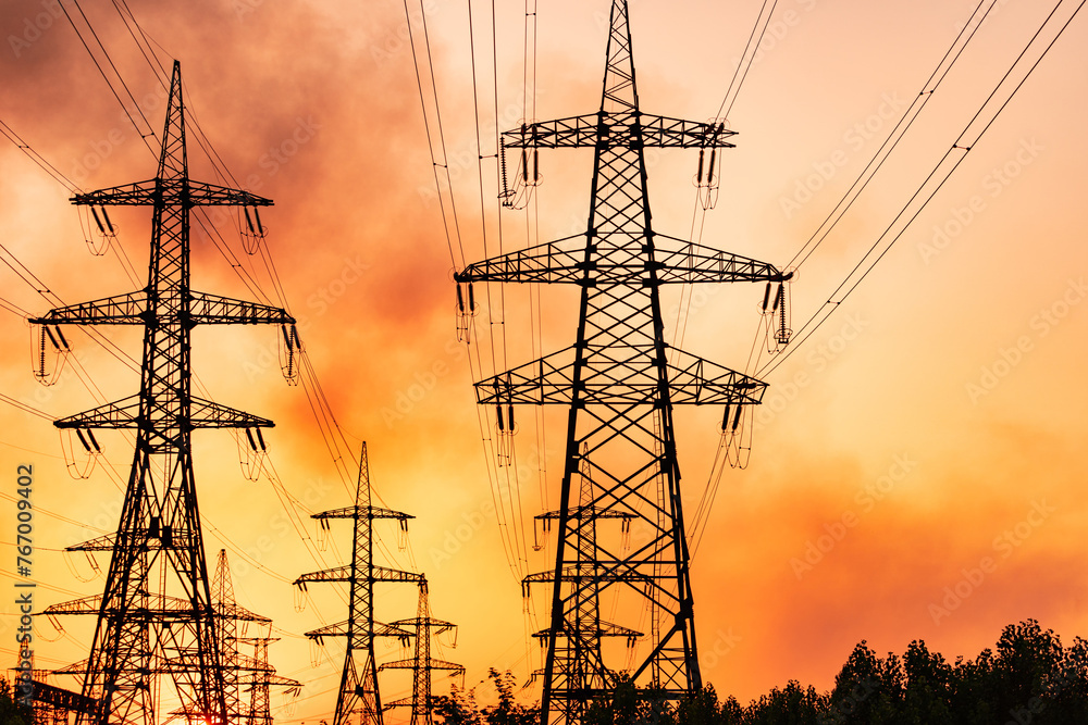 High voltage towers and power lines with red sky