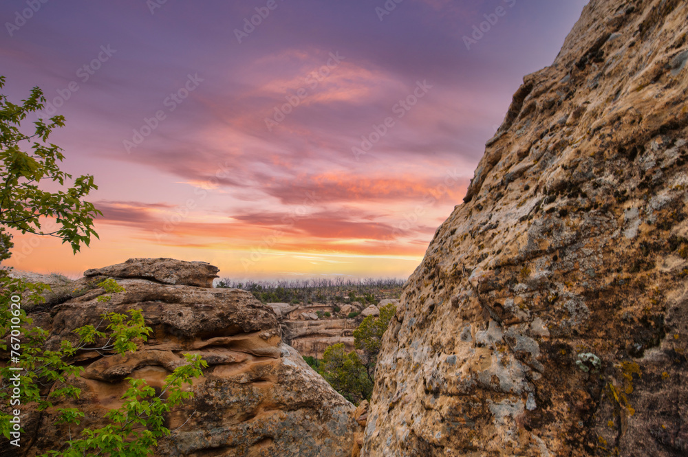 the mesmerizing hues of sunset sky, casting warm light over the textured rocky foreground and silhouetted trees