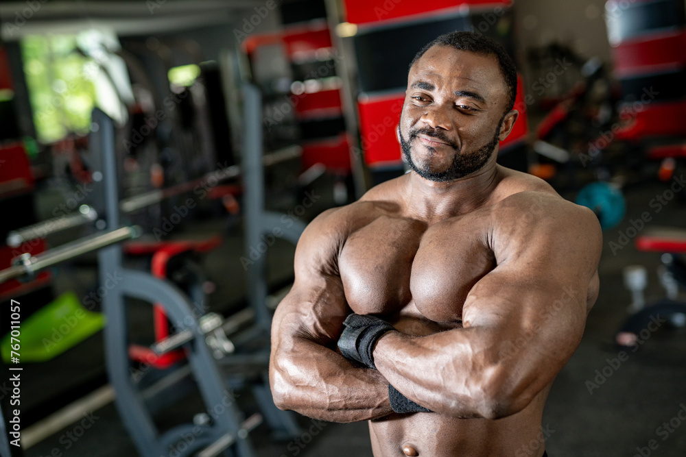 Portrait of muscular african american man posing with dumbbells in gym Portrait of muscular african american man posing with dumbbells in gym