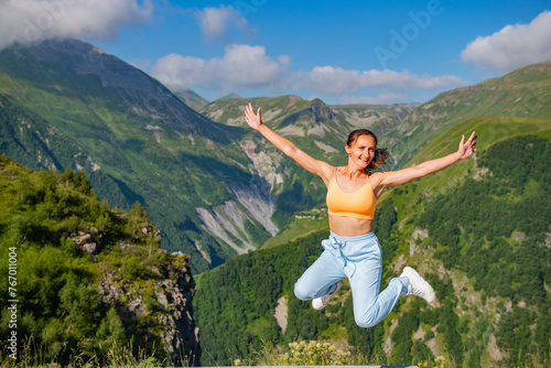 Woman Wearing Blue Suit Standing Against Breathtaking Mountain Background with Blue Sky and Trees