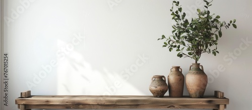 Ceramic art deco vases and a sign with room for text placed on a wooden bench against a white wall, creating a still life setup. This can serve as an inspiration for home decor,
