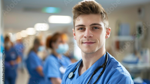 portrait of young male nurse in uniform with healthcare team in background