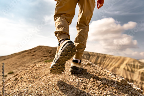 Close up photo of hiker legs and boots is walking uphill against blue sky