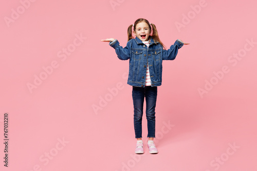 Full body little child kid girl 7-8 years old wears denim shirt have fun shrugging shoulders looking puzzled spread hands isolated on plain pink background. Mother's Day love family lifestyle concept.