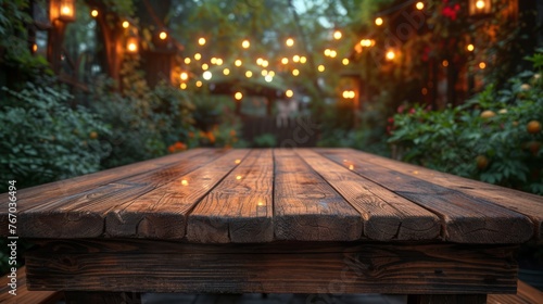   A wooden table rests in front of a lush forest  illuminated by suspended lights hanging overhead