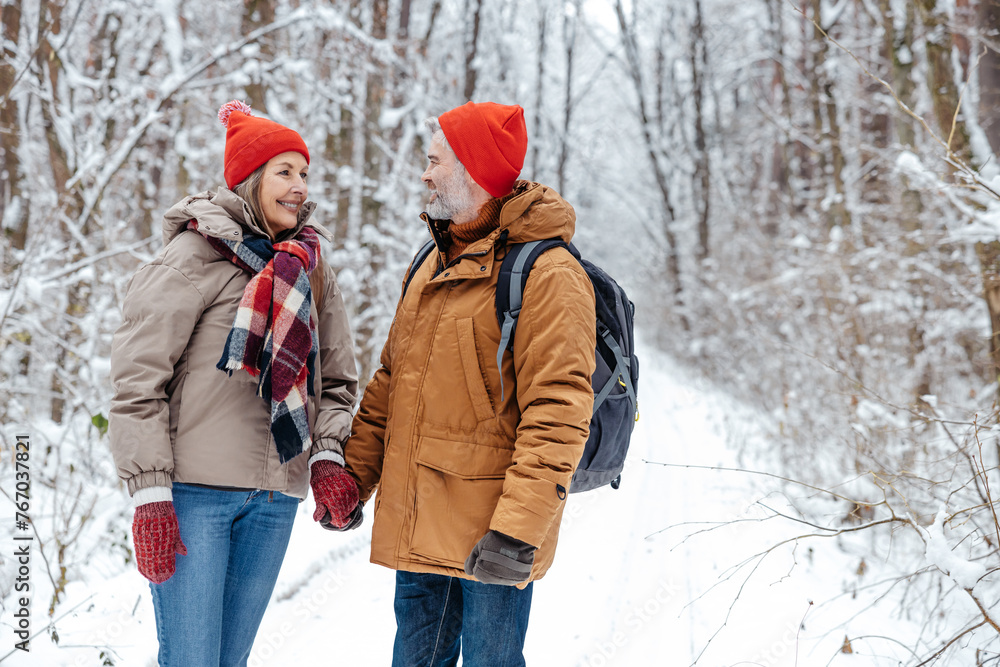Mature couple in a snowy forest feeling excited