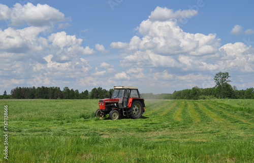 Traktor koszący trawę na łące, sianokosy