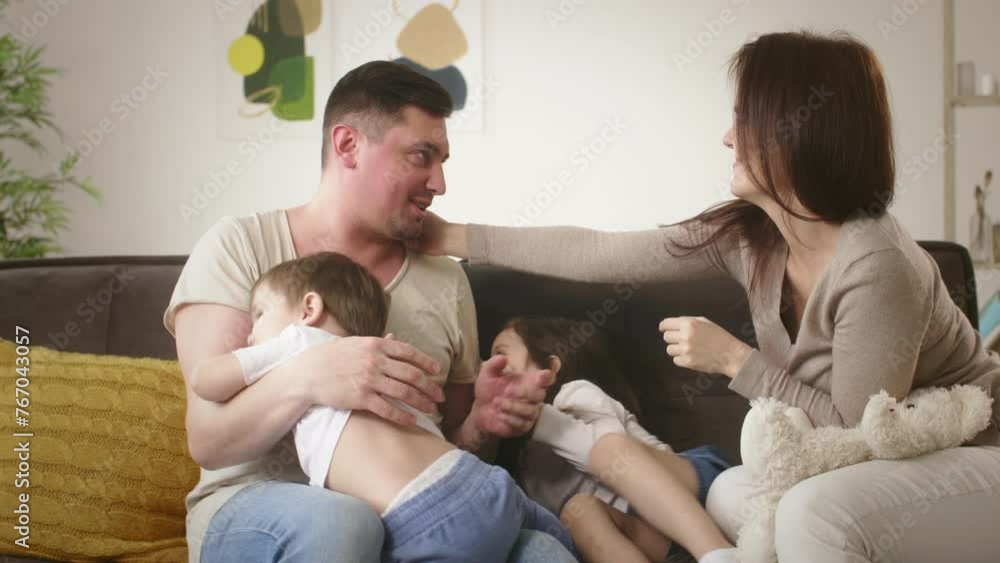 Family with little children plays tickling in living room Family with little children plays tickling in living room
