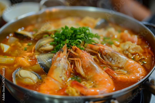 A bowl of soup with shrimp and other seafood. The soup is hot and steamy, and the shrimp are cooked and ready to eat. The dish looks delicious and inviting
