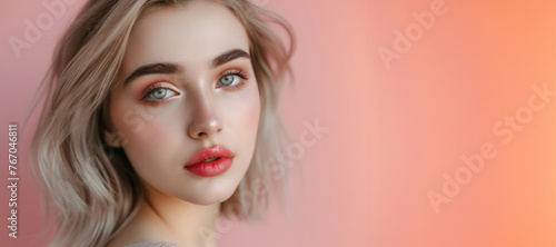 A woman with blonde hair and blue eyes is standing in front of a pink background. She is wearing red lipstick and has her hair pulled back. Concept of confidence and beauty