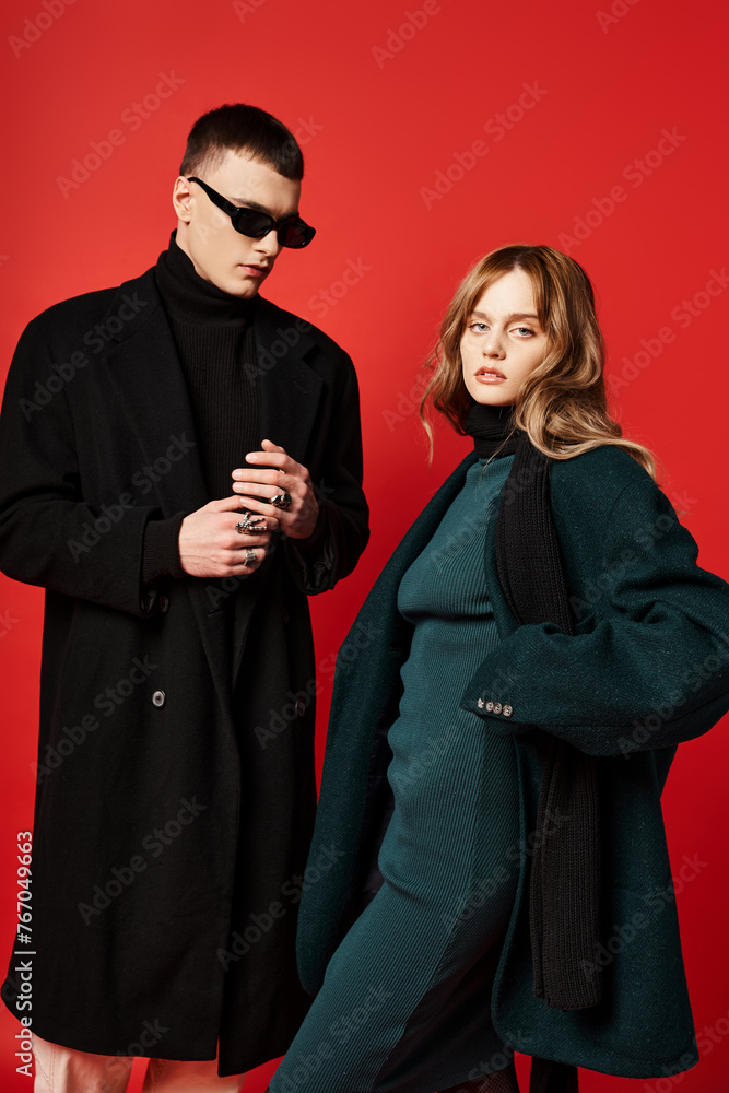 appealing long haired woman in elegant coat looking at camera near her boyfriend with sunglasses