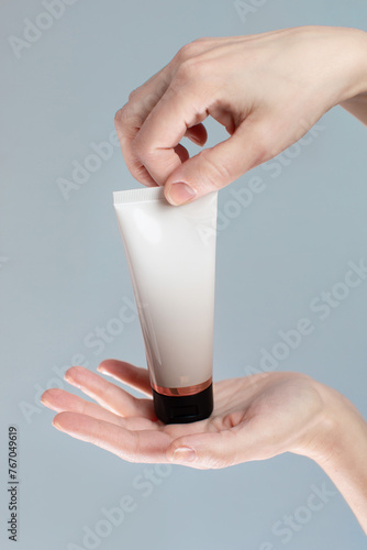 Woman hands holding hand cream on grey background