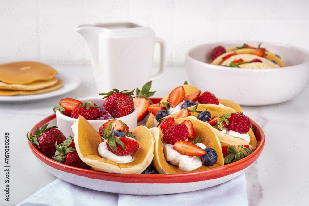 Pancake tacos. Portion of sweet dessert taco made with pancake, whipped cream, cottage cheese or ice cream, fruit and berries. Summer breakfast or brunch recipe, copy space