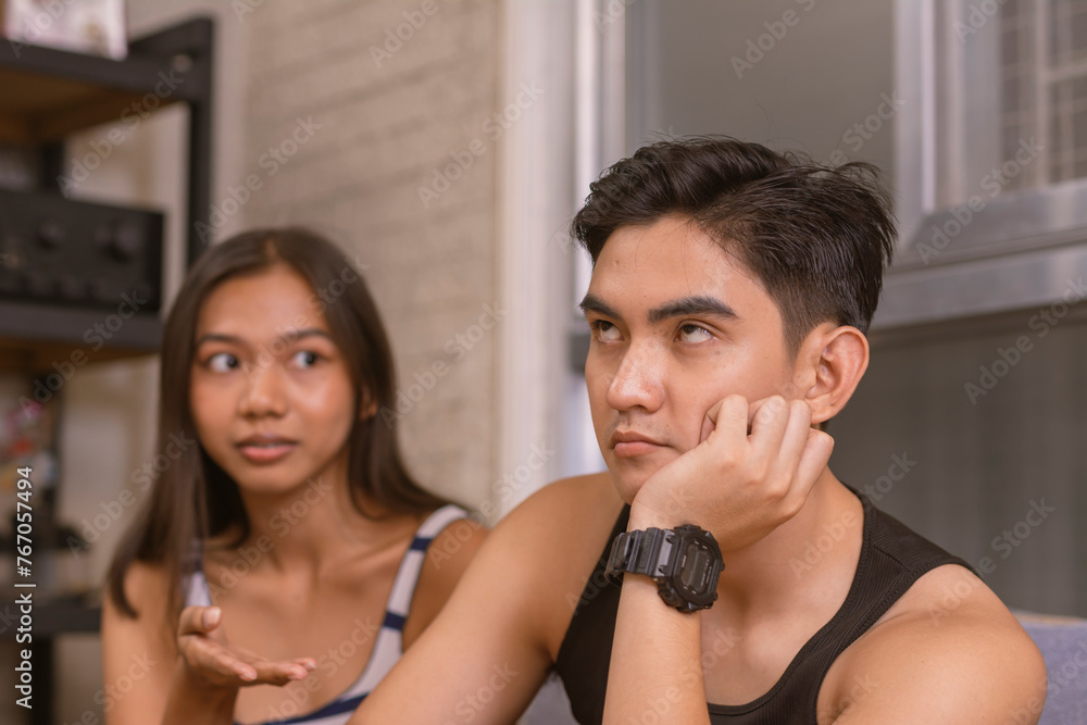 Eyerolling young Asian man shows contempt while ignoring his
