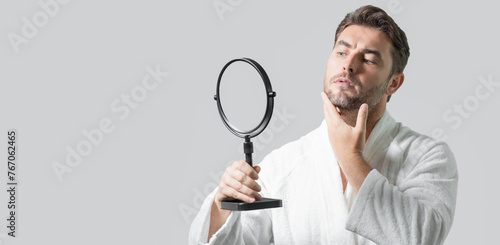 Banner with copy space of man touching chin and skin. Handsome man touching face in front of the mirror in bath. Perfect skin. Man cosmetic, skin treatment. Hygiene and skin care male face. © Volodymyr
