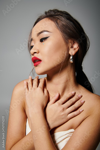 attractive asian young woman with red lips covering to neckline against grey background