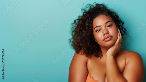 Young beautiful dark woman with natural makeup on a blue background. Beauty and skin care concept. Plus size model. © Kate