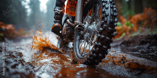 front wheel of a sports enduro motorcycle riding on a muddy road in forest in nature close-up