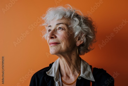 Portrait of a senior woman with grey hair on an orange background