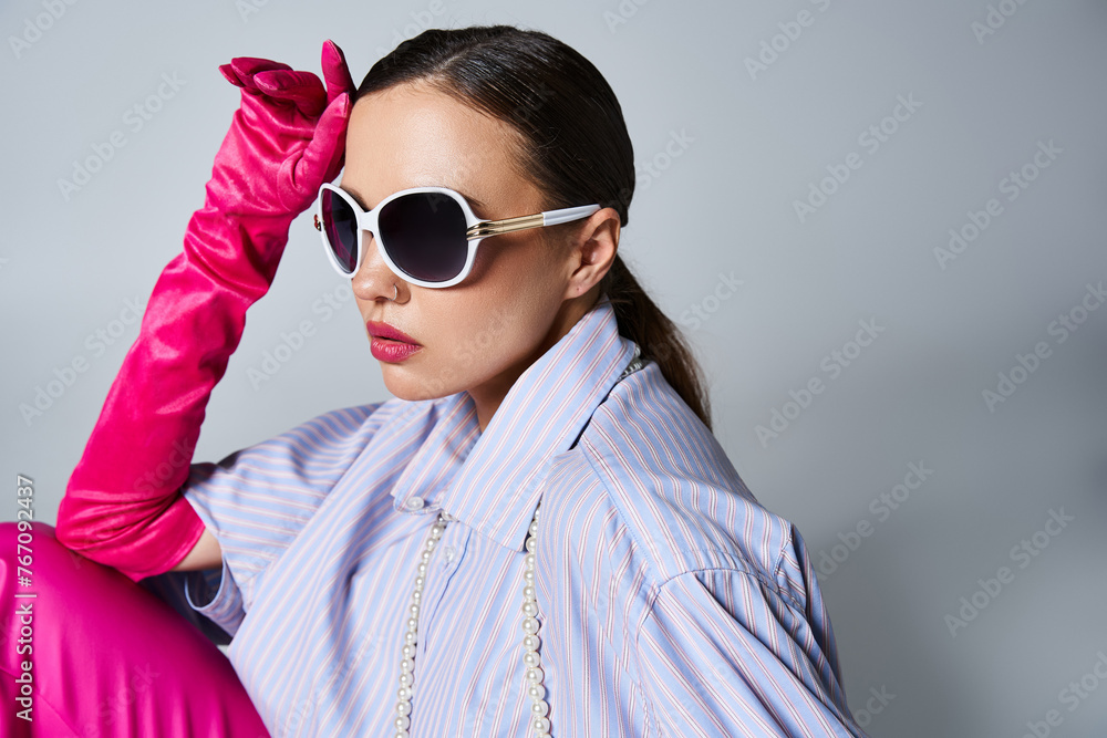 Pretty brunette girl in violet shirt and pearls, sunglasses and pink gloves touching her forehead Pretty brunette girl in violet shirt and pearls, sunglasses and pink gloves touching her forehead