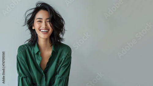 Malay woman wearing green shirt smiling laugh out loud isolated on grey