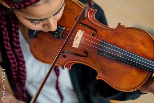musician with burgundy braids tuning a violin
