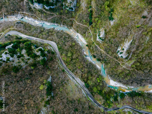 View from above of a narrow river behind a mountain forest