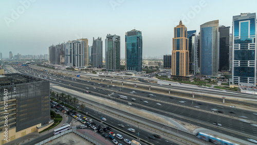 Aerial view of Jumeirah lakes towers skyscrapers day to night timelapse with traffic on sheikh zayed road.