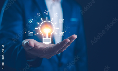 Photos Businessman holding a magnifying glass that illuminates a light bulb icon, representing insight, innovation, and the search for bright ideas in the corporate world