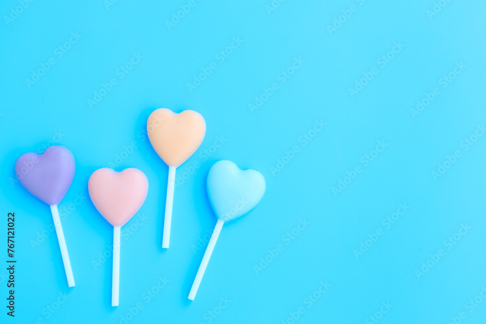 Multicolored heart shaped lollipop on blue background, Chocolate candy