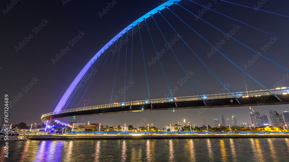 Obraz premium Futuristic Pedestrian Bridge over the Dubai Water Canal Illuminated at Night timelapse hyperlapse, UAE.